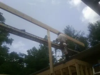 Carpenter setting a ridge beam over a new addition frame — Ice Dam Removal by Roofing Brothers in Grandin