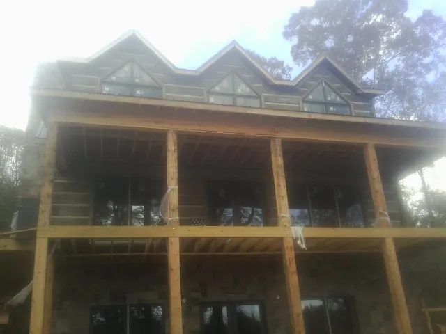 Dormers and porch framing on a large log home under construction — Roof Coating work by our crew in Grandin