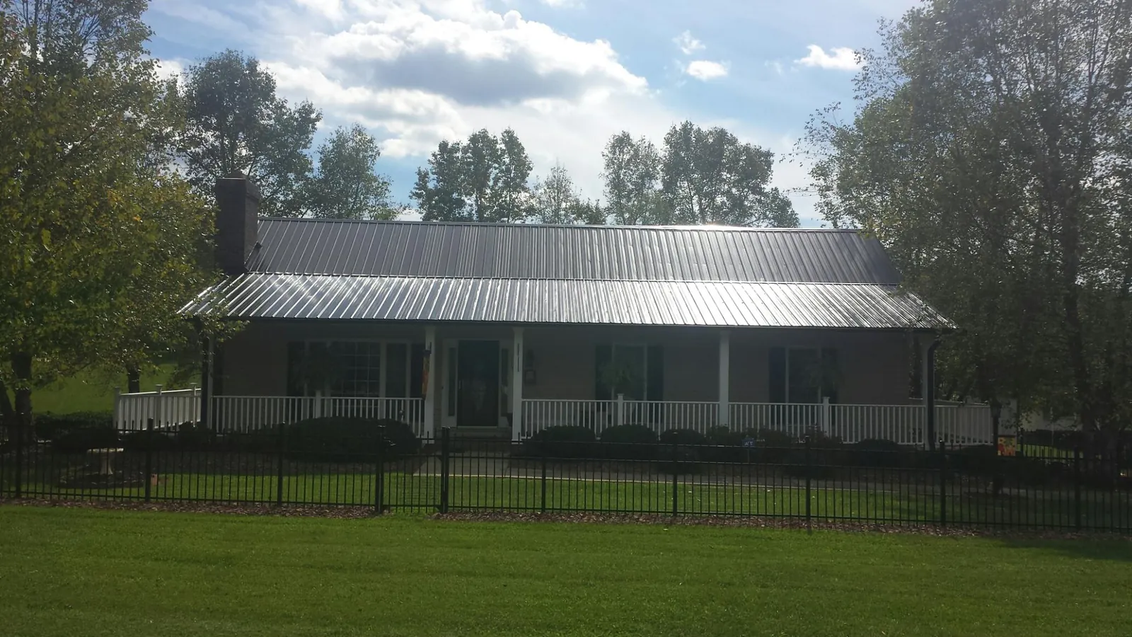 Gray metal roof on a brick ranch with a full width front porch — Gutter Guard Installation work by our crew in Grandin
