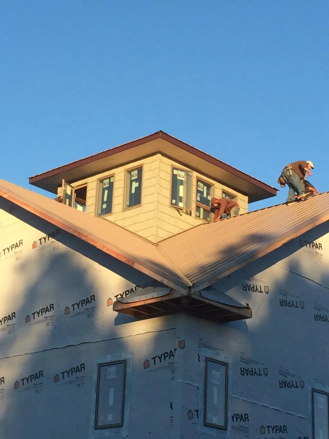 Roofers working around a rooftop cupola on a new metal roof at sunset — Roof Waterproofing in Grandin by Roofing Brothers